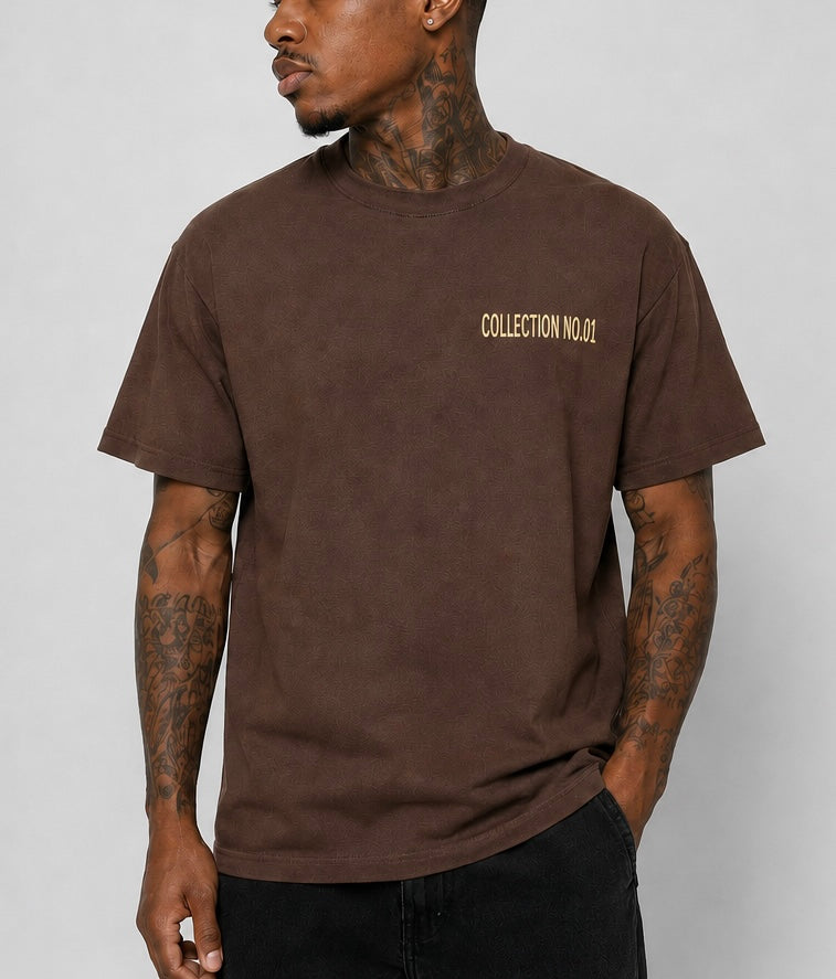 A man wearing a brown short-sleeve t-shirt with 'COLLECTION NO.01' printed in gold on the left chest, paired with black jeans against a neutral gray background.